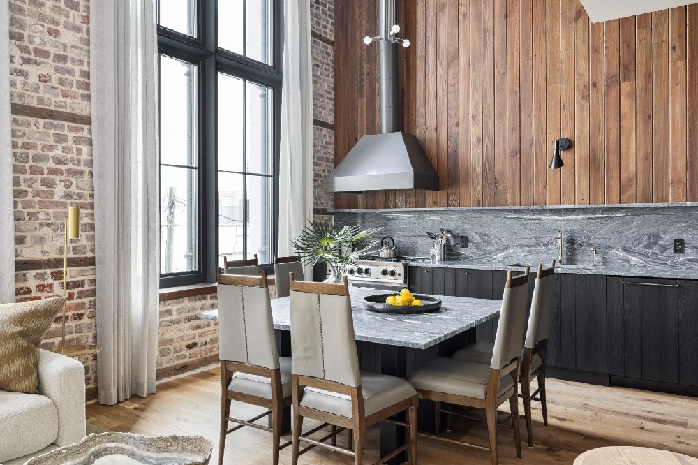 Contemporary kitchen featuring marble island, dark wood cabinets, exposed brick walls and oversized windows